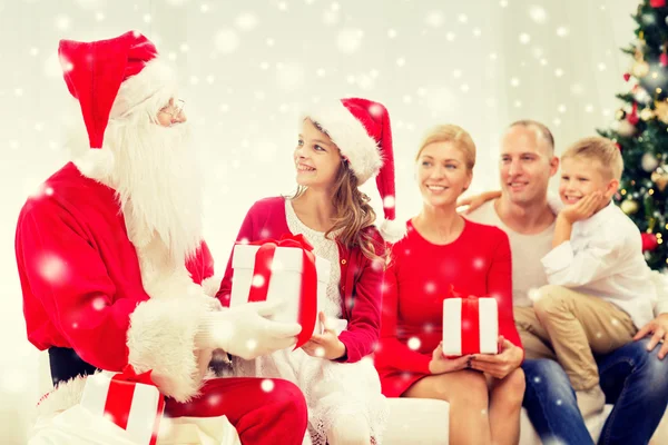 Família sorridente com Papai Noel e presentes em casa — Fotografia de Stock