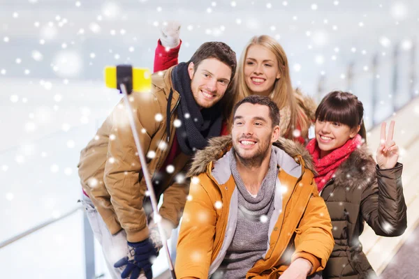 happy friends with smartphone on skating rink