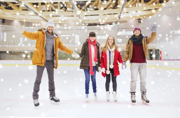 Amigos felices agitando las manos en la pista de patinaje — Foto de Stock