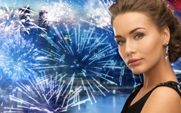 Schöne Frau trägt Ohrringe über Feuerwerk — Stockfoto