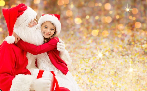 Smiling girl cuddling with santa claus over lights — ストック写真