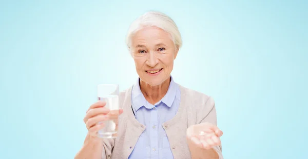 Счастливая пожилая женщина с водой и лекарствами — стоковое фото