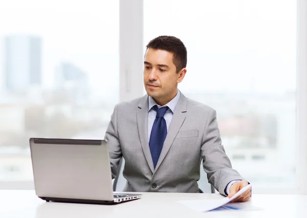 Zakenman met laptop en papieren — Stockfoto