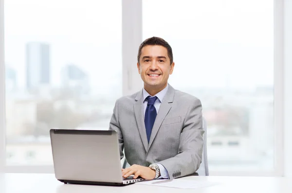 Homem de negócios sorridente com laptop e papéis — Fotografia de Stock