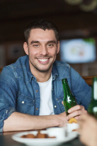 Счастливый молодой человек пьет пиво в баре или пабе — стоковое фото