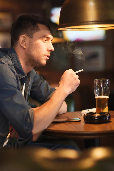 Mann trinkt Bier und raucht Zigarette an Bar — Stockfoto