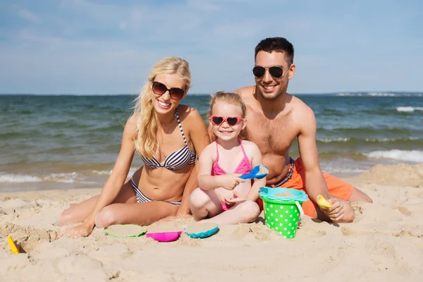Счастливая семья играет с песочными игрушками на пляже — стоковое фото