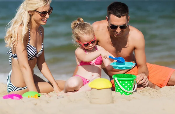 Familia feliz jugando con juguetes de arena en la playa — Foto de Stock