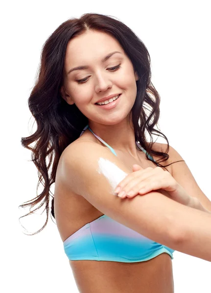 Mujer joven feliz en traje de baño aplicando protector solar —  Fotos de Stock