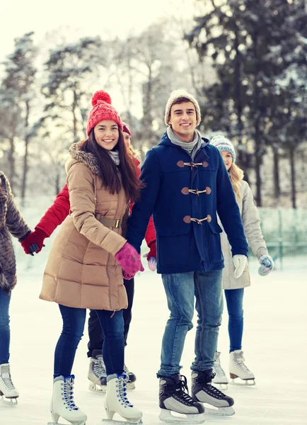 Amigos felices patinaje sobre hielo en pista al aire libre —  Fotos de Stock