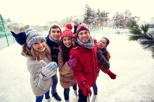 Amigos felices con smartphone en pista de patinaje sobre hielo — Foto de Stock