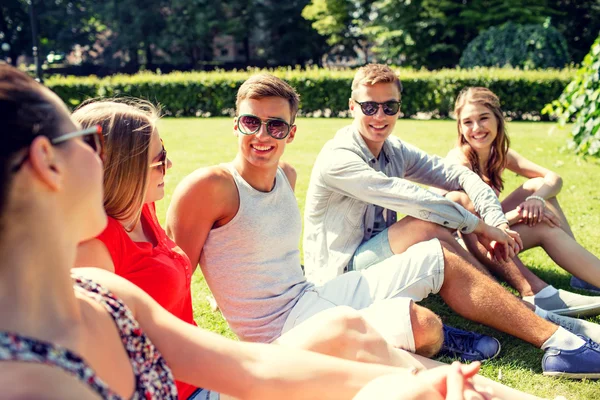 Groupe d'amis souriants à l'extérieur assis dans le parc — Photo