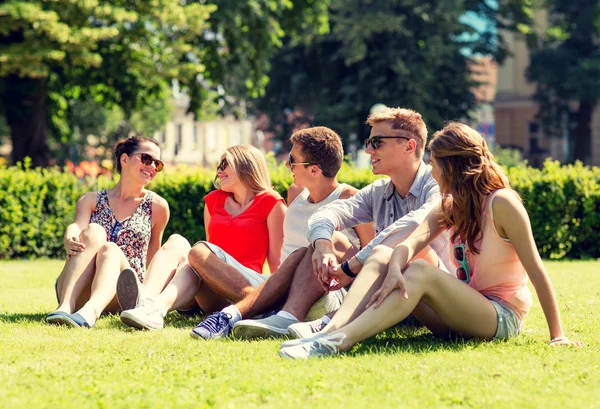 Groep lachende vrienden buiten zitten op gras — Stockfoto