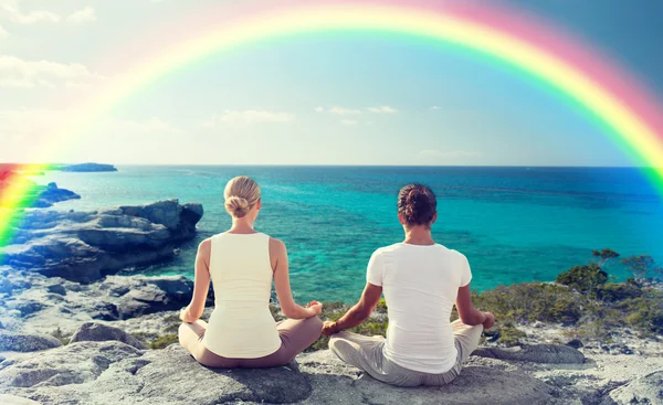 Casal feliz meditando em lótus posar na praia — Fotografia de Stock