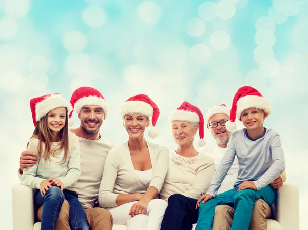 Família feliz em santa helper chapéus sentados no sofá — Fotografia de Stock