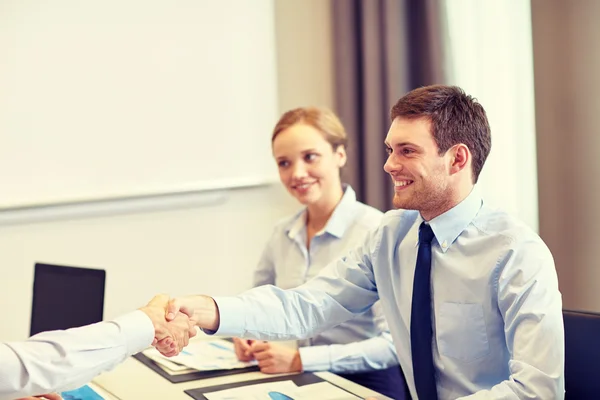 Smiling business team shaking hands in office — Stock Photo, Image