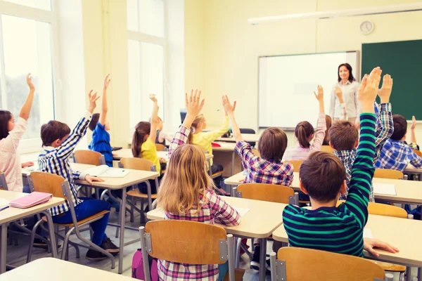 Groep van school kinderen verhogen handen in klas — Stockfoto