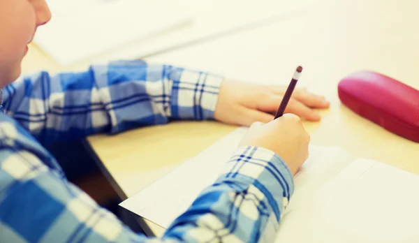 Close up of schoolboy writing test at school — ストック写真