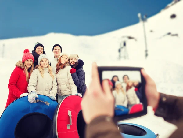 Lachende vrienden met sneeuw buizen en tablet pc — Stockfoto