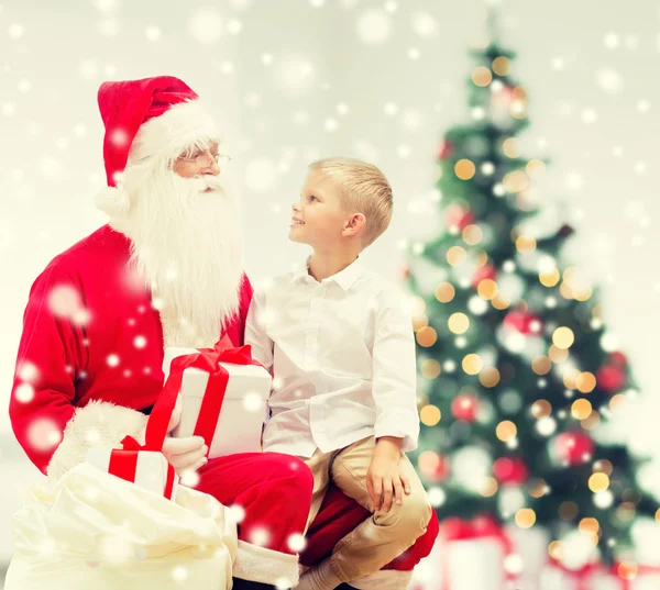 Niño sonriente con santa claus y regalos — Foto de Stock