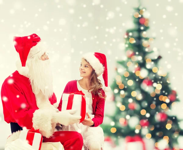 Niña sonriente con santa claus y regalos — Foto de Stock