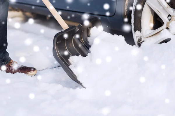 Primer plano del hombre excavando nieve con la pala cerca del coche —  Fotos de Stock