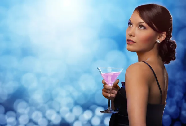 Smiling woman holding cocktail over blue lights — Stock Photo, Image