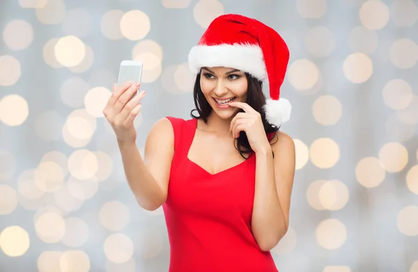 Woman in santa hat taking selfie by smartphone — Stock Photo, Image