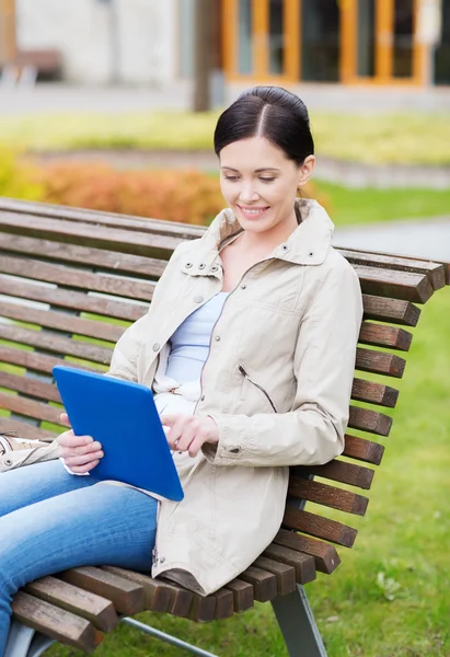 Kobieta z komputera typu tablet, siedząc na ławce w parku — Zdjęcie stockowe