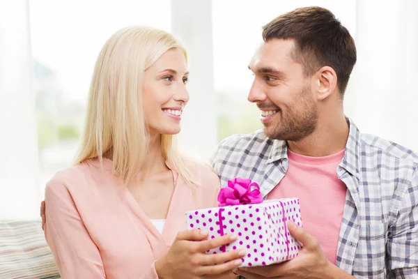 Happy man giving woman gift box at home — Stock Photo, Image