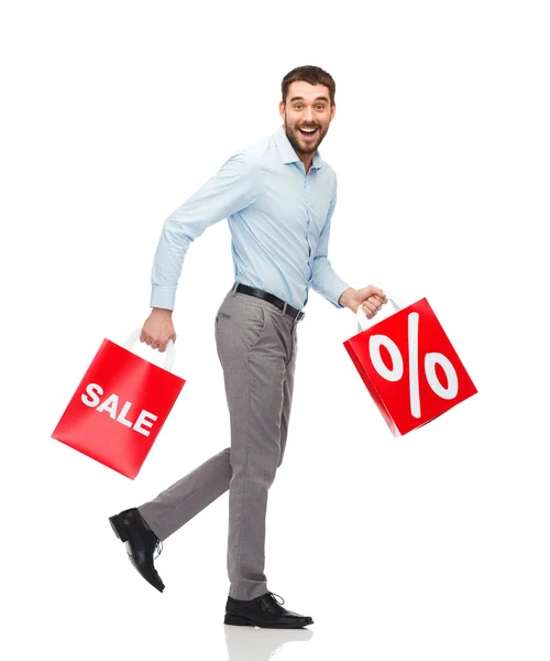 Smiling man walking with red shopping bag — Stockfoto