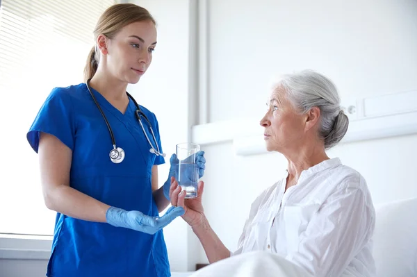 Enfermeira dando remédio para a mulher idosa no hospital — Fotografia de Stock