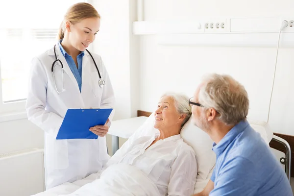 Senior woman and doctor with clipboard at hospital — Stock Photo, Image