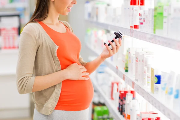 Gelukkig zwangere vrouw met medicatie bij apotheek — Stockfoto