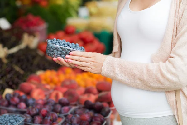 Těhotná žena nákupu borůvky na tržišti — Stock fotografie