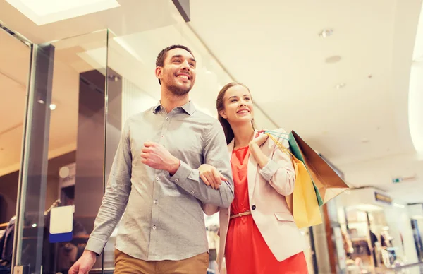 Feliz jovem casal com sacos de compras no shopping — Fotografia de Stock