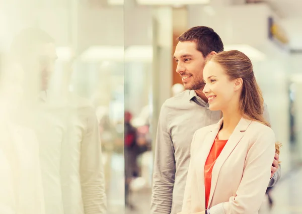 Happy couple looking to shop window in mall — Stock Photo, Image