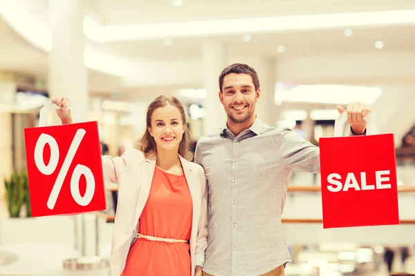 Glückliches junges Paar mit roten Einkaufstüten in Einkaufszentrum — Stockfoto