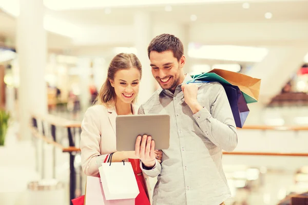 Casal com tablet pc e sacos de compras no shopping — Fotografia de Stock