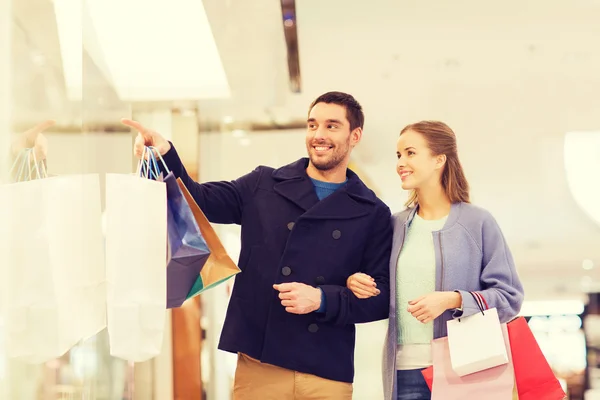 Szczęśliwa młoda para z torbami na zakupy w centrum handlowym — Zdjęcie stockowe