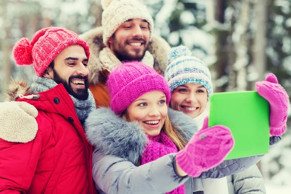 Smiling friends with tablet pc in winter forest — Stock Photo, Image
