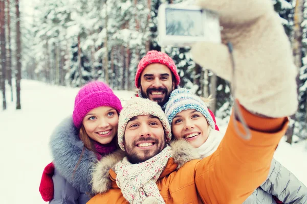 Усміхнені друзі з камерою в зимовому лісі — стокове фото