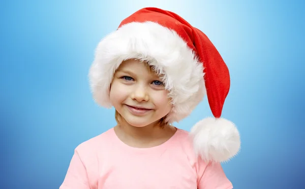 Sorridente bambina in cappello di Babbo Natale sopra blu — Foto Stock