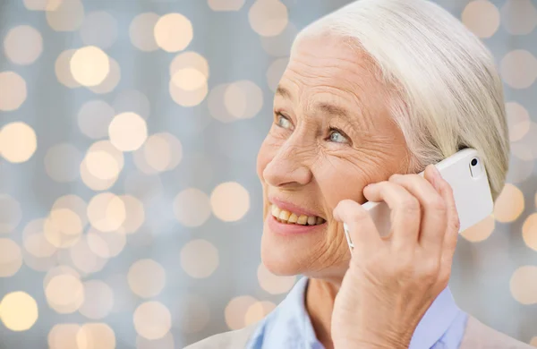 Senior woman with smartphone calling over lights — Zdjęcie stockowe