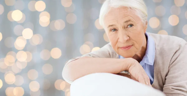 Happy senior woman resting on sofa over lights — Stockfoto