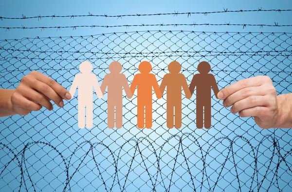 Hands holding people pictogram over barb wire — Stockfoto