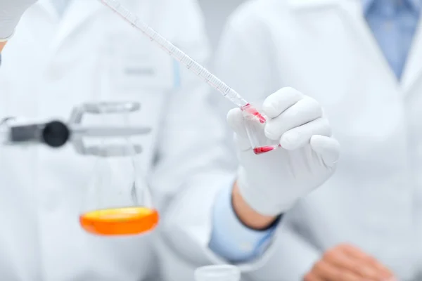 Primer plano de los científicos que llenan el tubo de ensayo en laboratorio — Foto de Stock