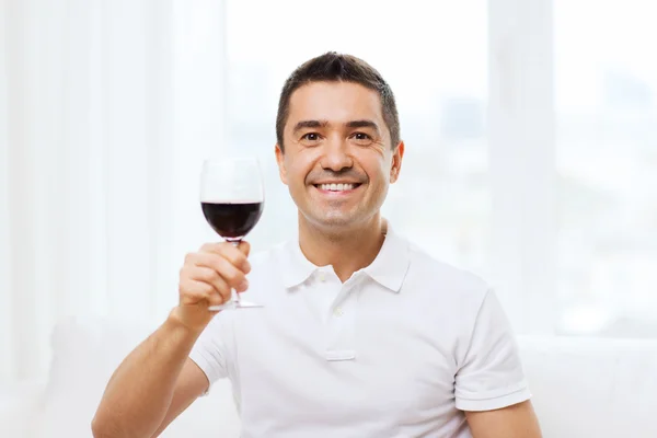 Glücklicher Mann, der zu Hause Rotwein aus Glas trinkt — Stockfoto