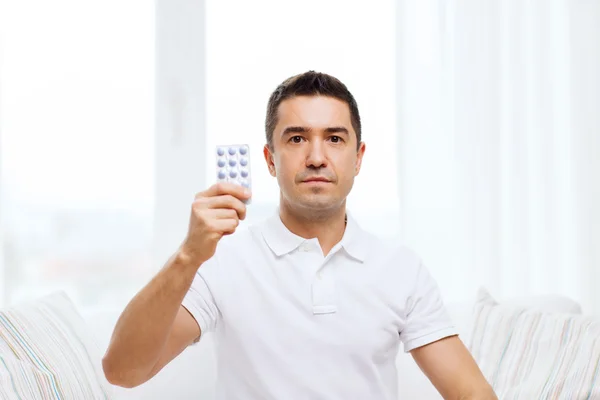 Uomo che mostra pacchetto di pillole a casa — Foto Stock