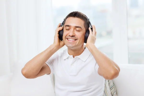 Счастливый человек в наушниках слушает музыку дома — стоковое фото